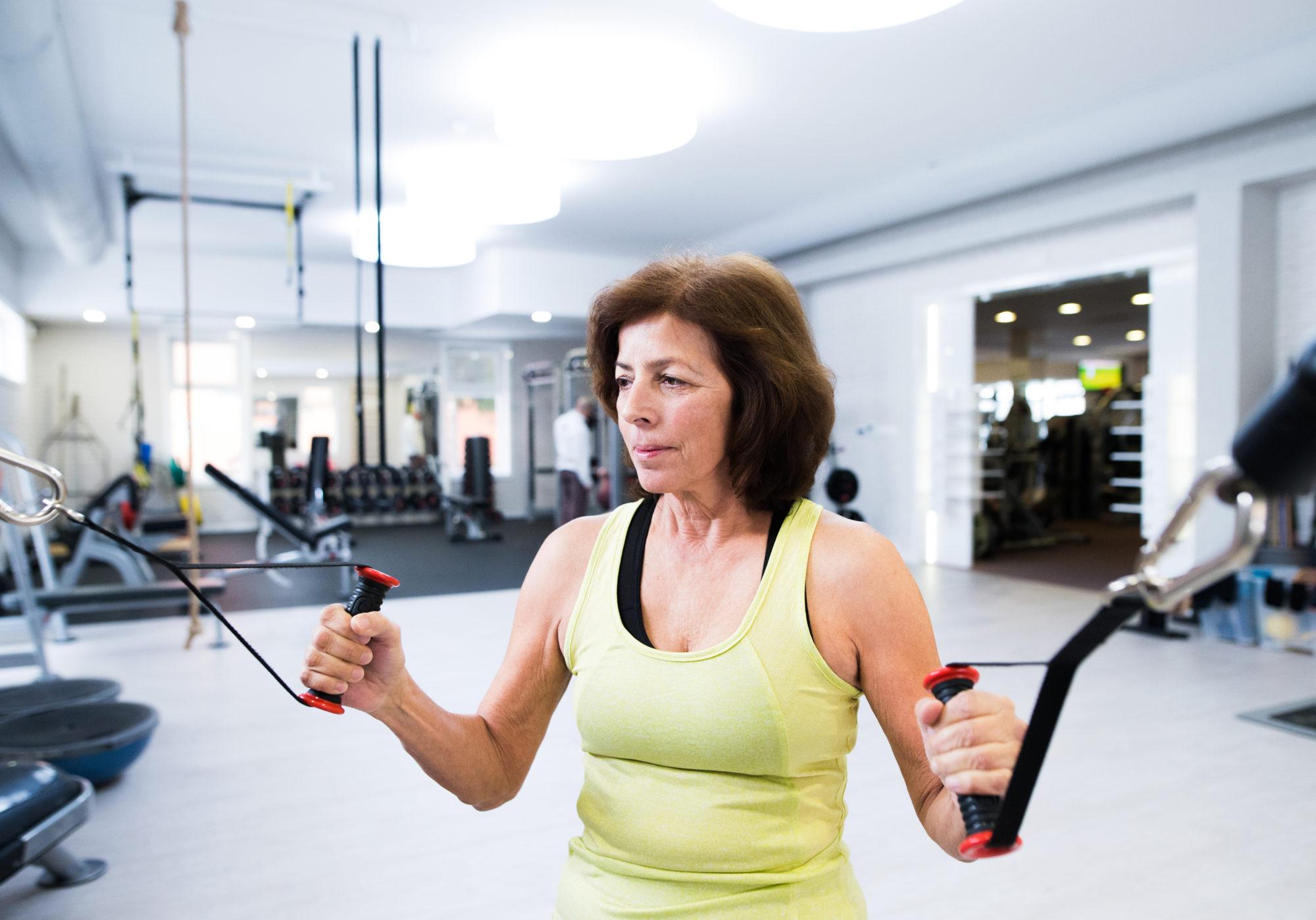 Senior woman in gym working out with weights.